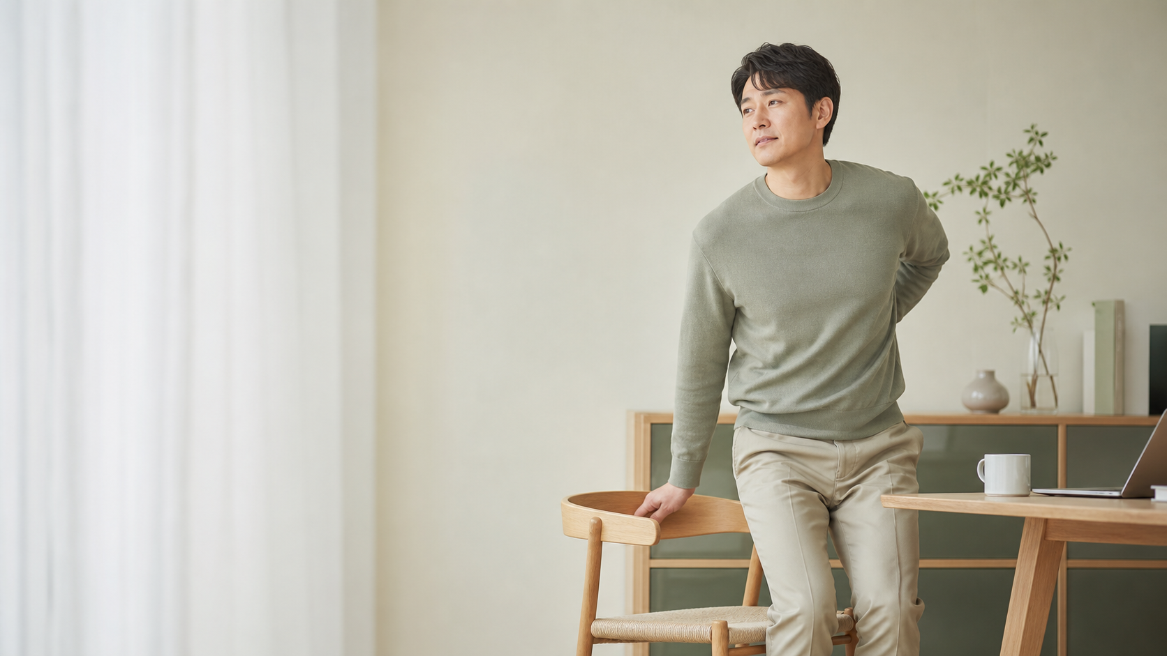 의자에서 천천히 일어나며 허리와 다리 움직임을 살피는 모습